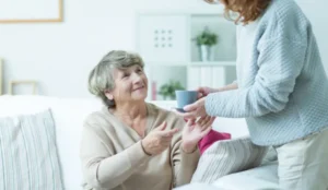 daughter giving coffee to mom who is on the couch