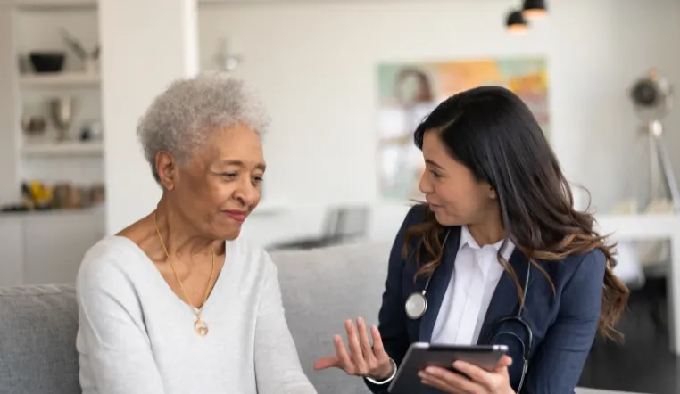 nurse and older lady looking at tablet talking