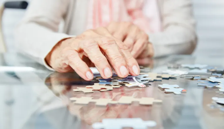 senior hands playing with puzzle pieces