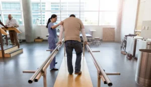man using rehab equipment with help from nurse
