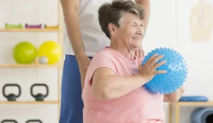 senior holding ball smiling for rehab