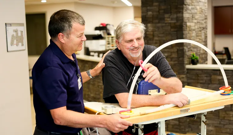 man using rehab equipment with the guidance of staff