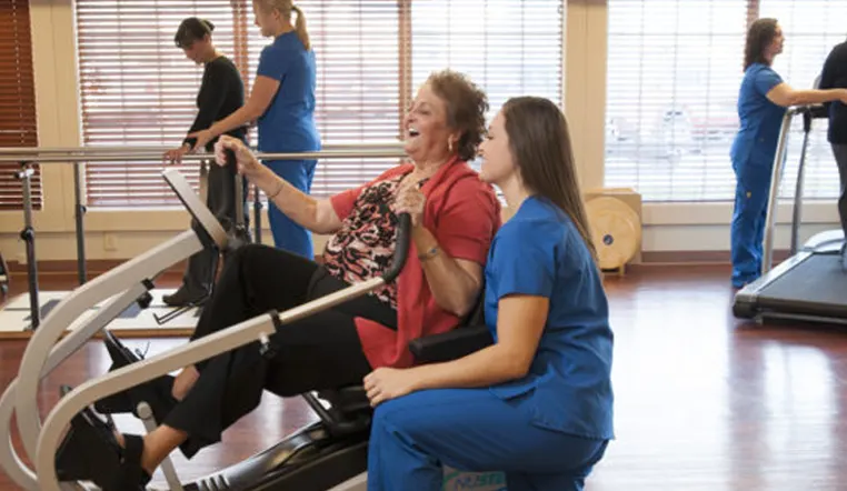 lady on rehab equipment with nurse supervision