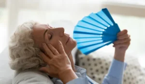 senior holding a fan to cool herself down