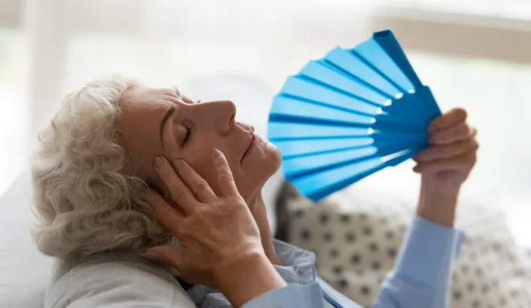 senior holding a fan to cool herself down