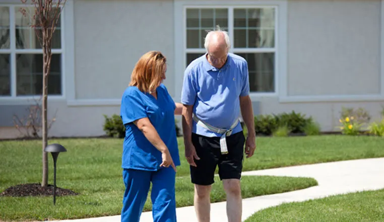 nurse and senior man walking outside
