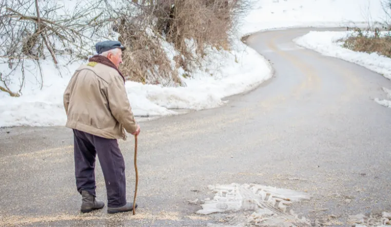 senior man walking on a road in the winter