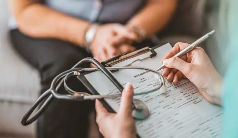 doctor writing on a document on a clipboard