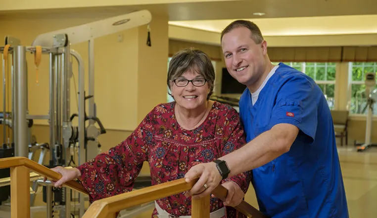 senior getting help while using rehabilitation machine