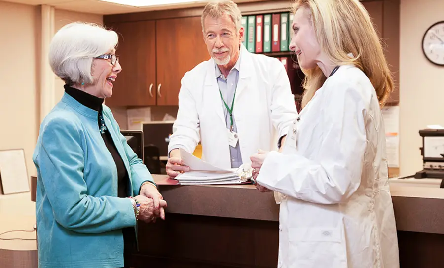 Female doctor speaks to female resident while male doctor looks on