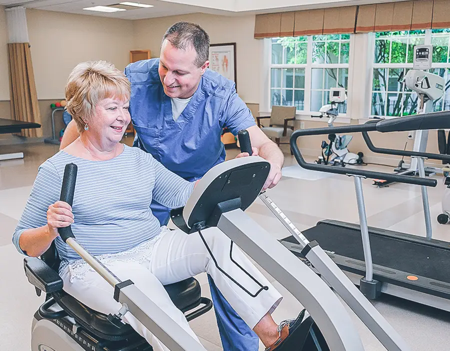 Therapist works with female patient on recumbent bike