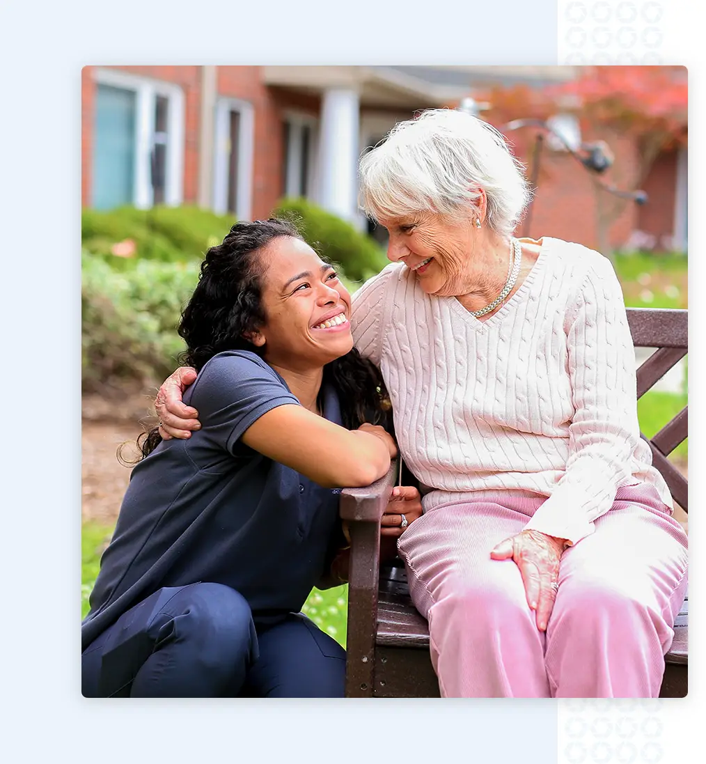 Nurse smiles up at a resident in pink