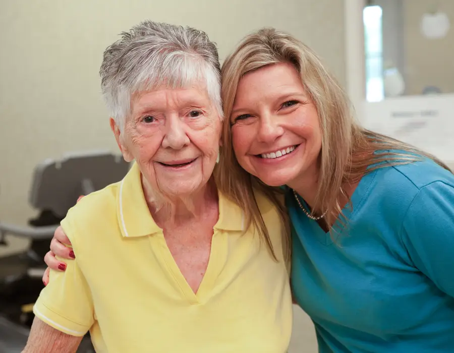 Smiling senior woman with short hair alongside adult daughter