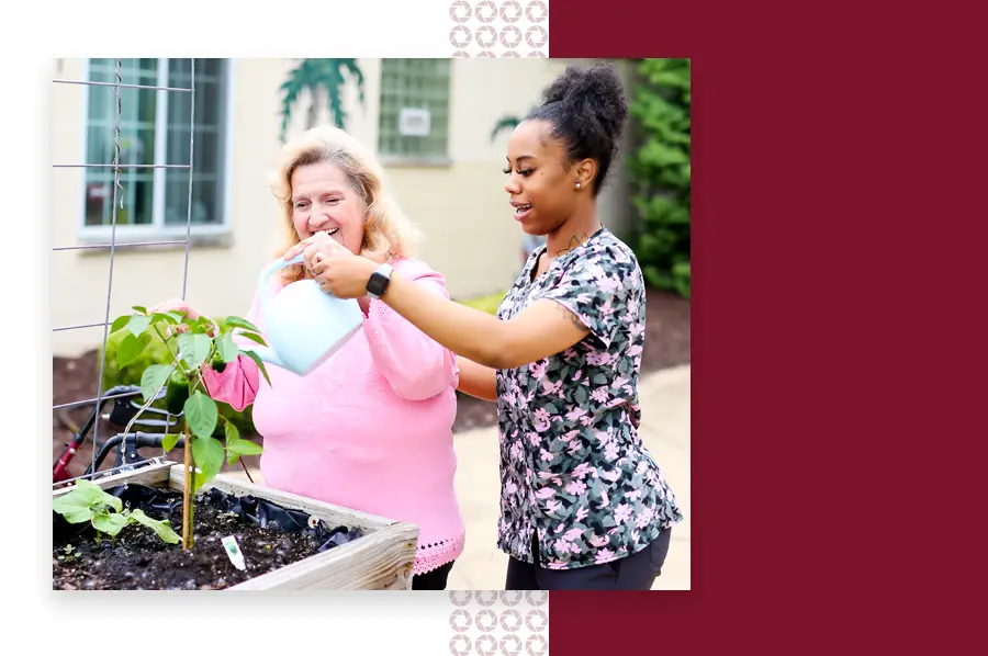 Female nurse helping a resident water a plant outside