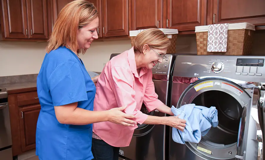 Physical therapist works with a patient on occupational therapy putting clothes into dryer