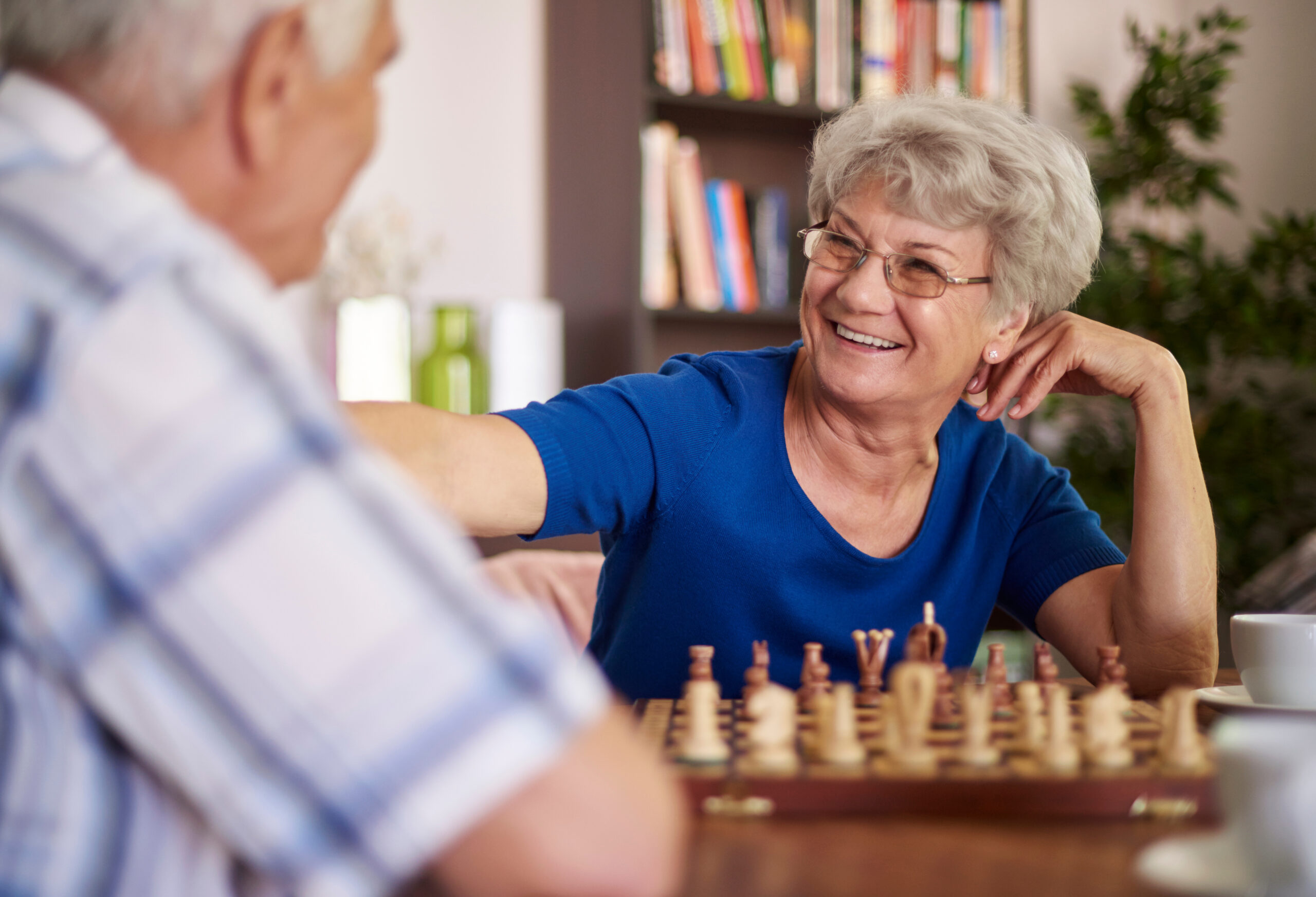 Senior woman smiling as she plays chess with man